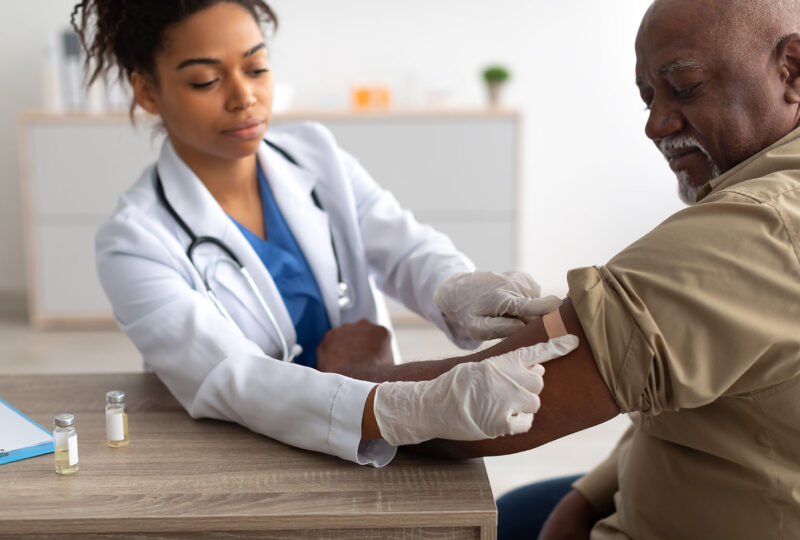 doctor or nurse putting bandage on man's arm after vaccination