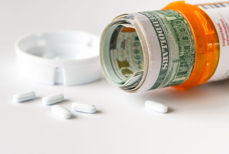 prescription pill bottle with bills spilling out and cash inside