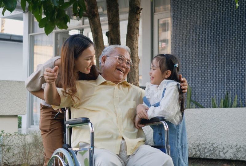 Disabled senior grandpa on wheelchair with grandchild and mother