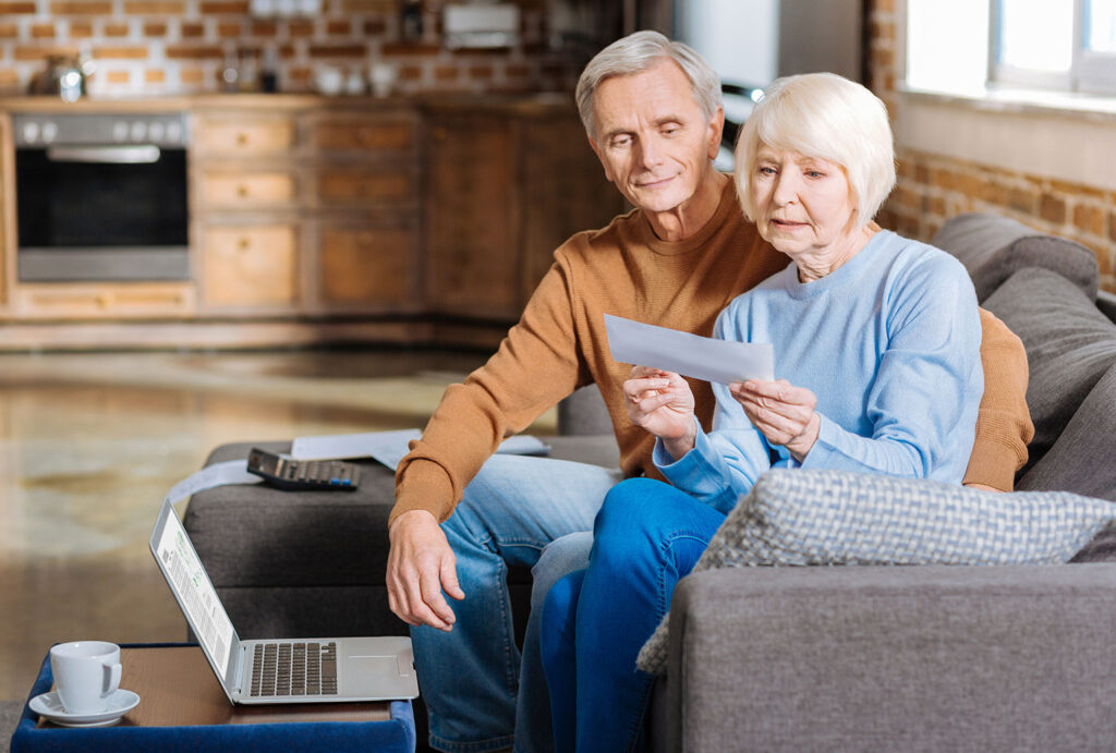 older couple on couch looking at a check