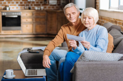 older couple on couch looking at a check