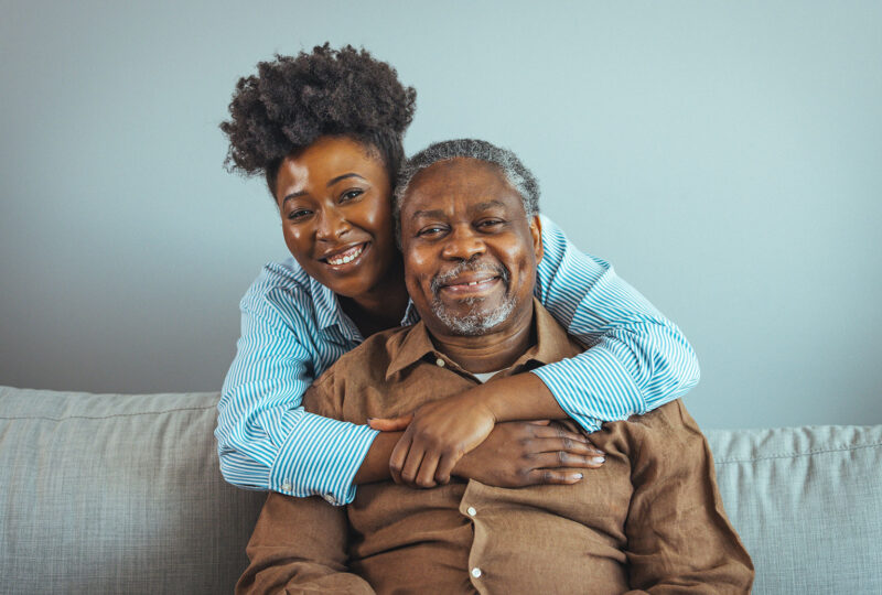 smiling young woman with arms around smiling older father