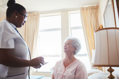 Female care worker nurse assists an elderly female patient with medicines for the day