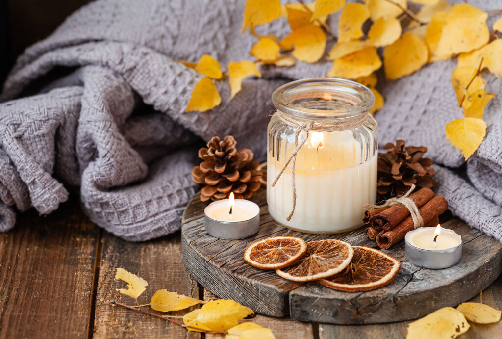 Autumn composition with aromatic candle, dry citrus, cinnamon