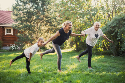 three generations of women balancing on one foot in the grass