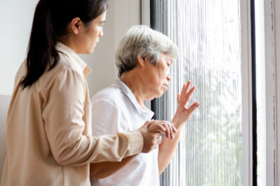 older woman holding nurse's hand and looking out a window