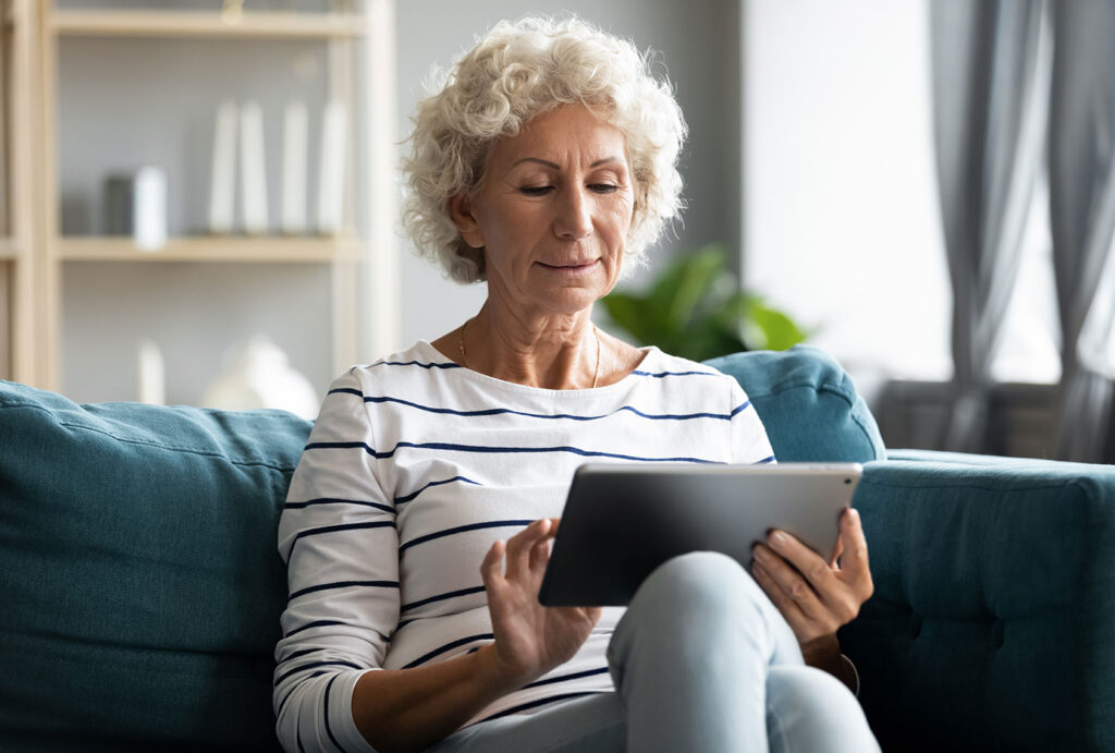 older woman sitting on couch using tablet