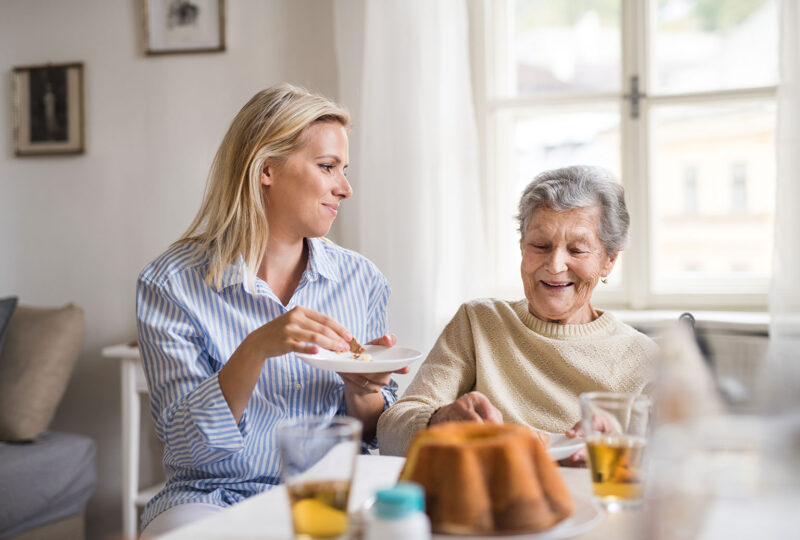 senior woman eating with caregiver