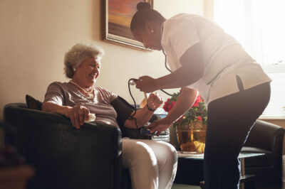 Nurse measuring blood pressure of senior woman patient at home
