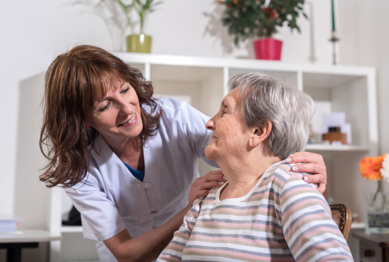 Nurse with her hands on the shoulders of a senior woman