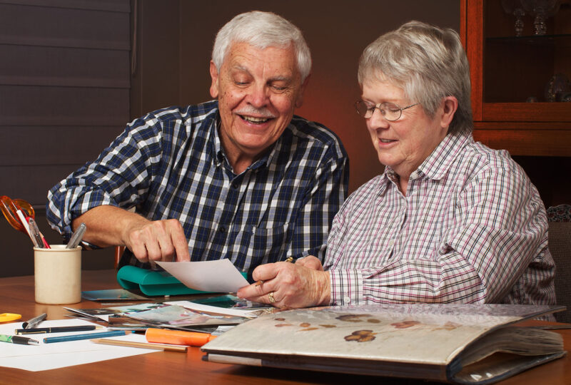 Happy senior married couple sharing memories while working on memory board