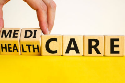 Medicare or healthcare symbol. Doctor turns cubes, changes the word 'healthcare' to 'medicare'. Yellow table, white background.