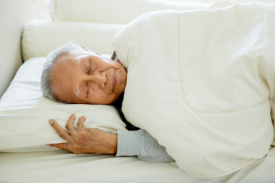 senior man asleep on his side in bed