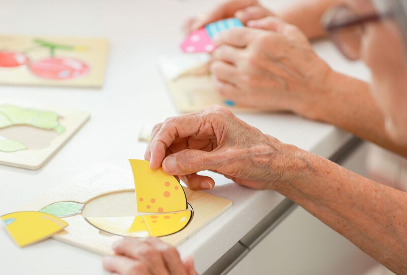 close up of older person putting together puzzle