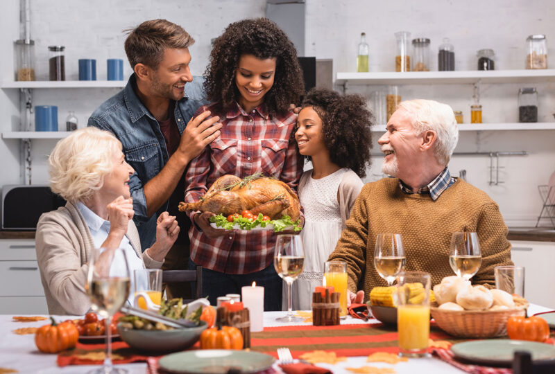 multi-generational family thanksgiving, mom bringing turkey to grandparents at the table