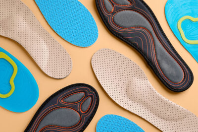 Many different shoe insoles on pale orange background, flat lay
