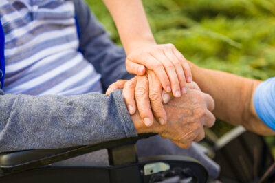 holding senior person's hands in wheelchair