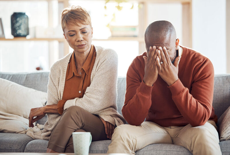 upset, stressed out couple sitting on couch together