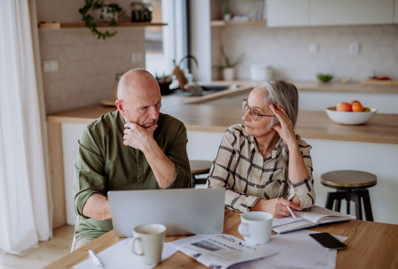 Stressed senior couple calculate expenses or planning budget together at home.