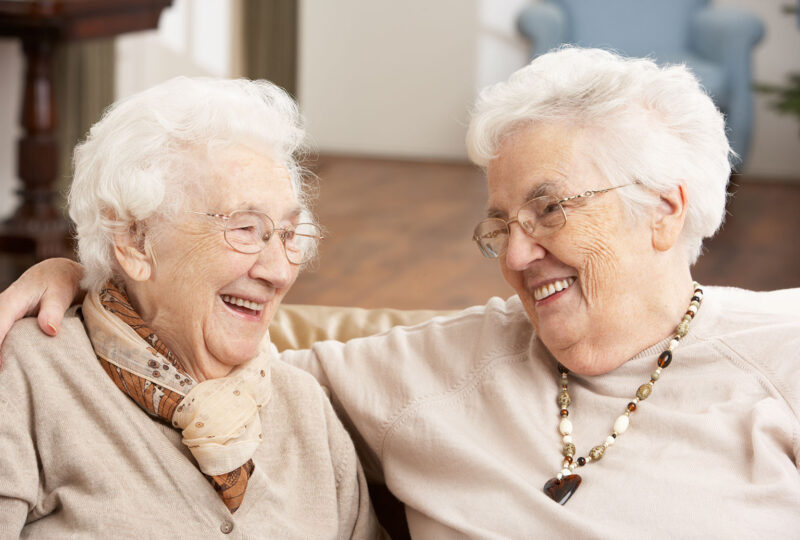 two happy senior women smiling at each other