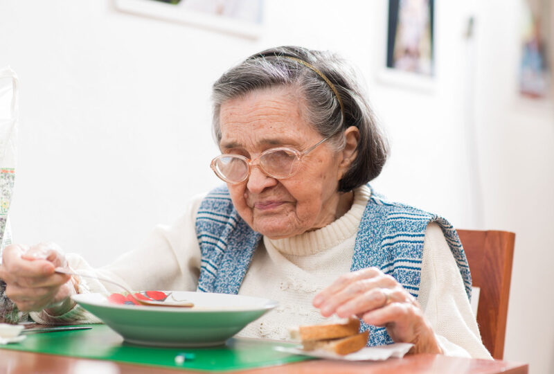 older woman eating soup at a table
