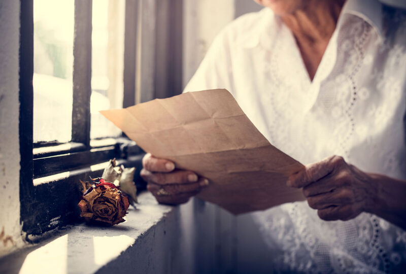 woman sitting by window reading letter