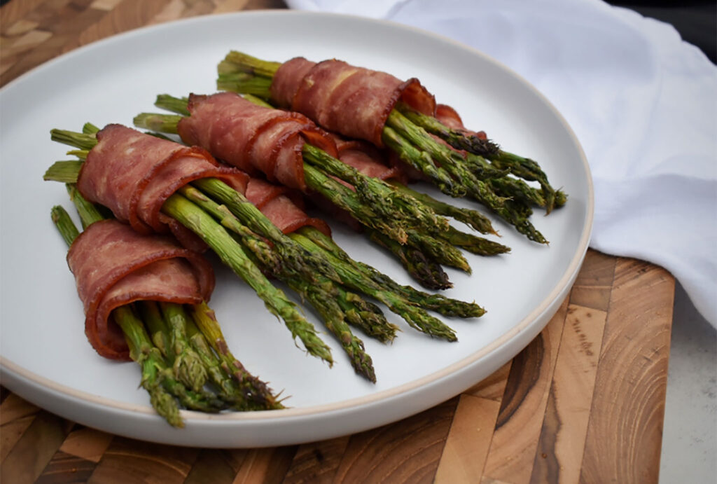 asparagus spears on a plate wrapped with bacon