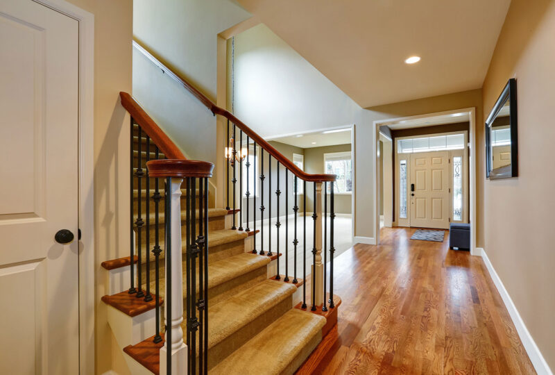 home with bright entrance hall accented with ornate sidelights framing the front door, view from the staircase