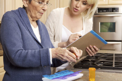 Senior Woman being helped with organizing prescription medicine by a young caregiver
