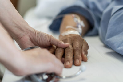 someone holding the hands of someone in a hospital bed with tubes in their arm