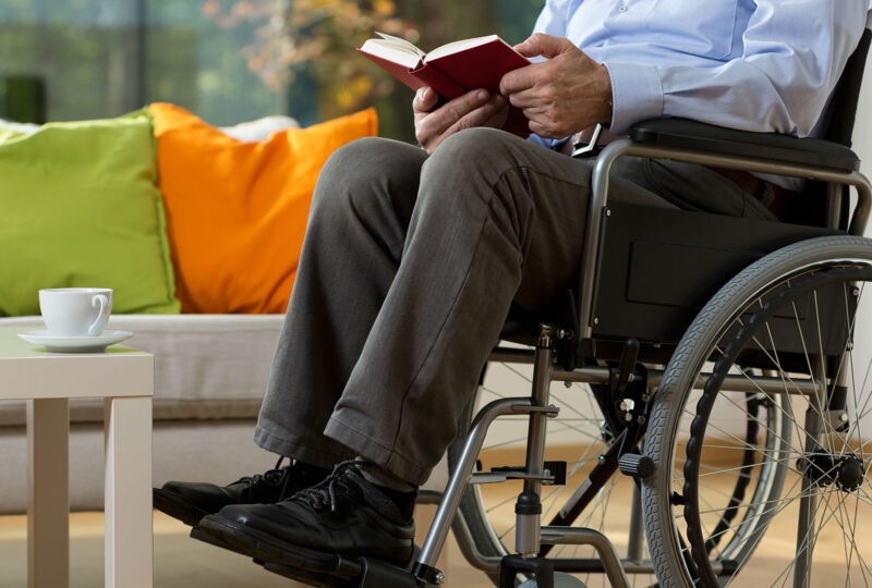Close-up of man using wheelchair reading book