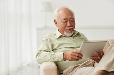 man sitting inside reading on a tablet
