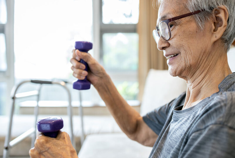 Happy smiling senior woman working out with dumbbells