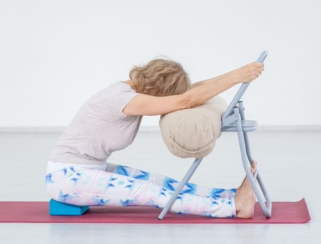 women doing adaptive yoga pose forward fold with chair