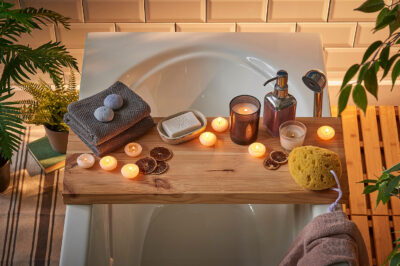 bath caddy covered with candles and accessories over a tub