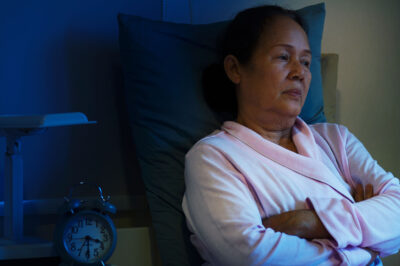 woman having sleep disorder, sitting in bed look sad.