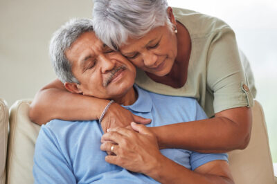 older adult couple hug, comfort or support in a living room at home.