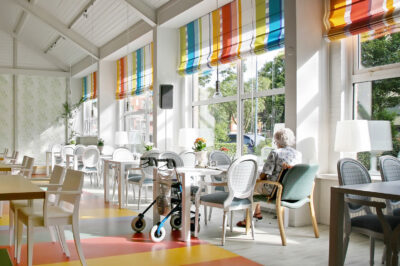 woman in the dining area of a bright and colorful senior living facility