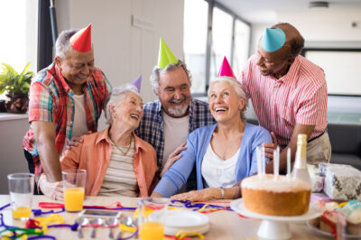 Cheerful friends looking at excited senior woman during birthday party
