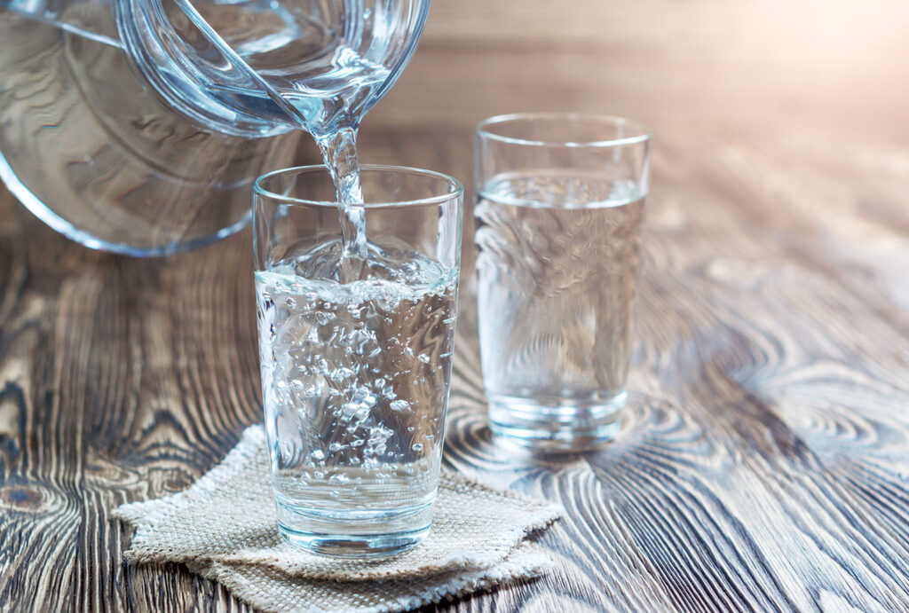 Glass of water on a wooden table. Water was poured into the beaker. Selective focus.