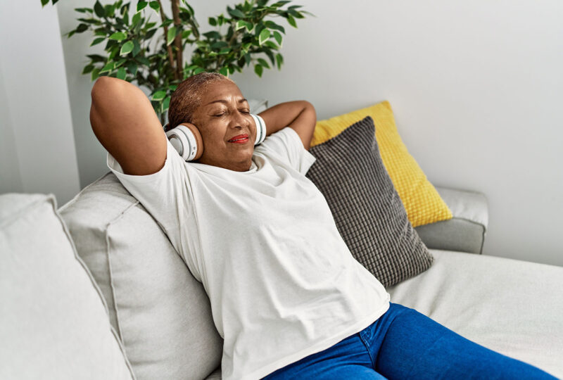 woman laying back on couch listening to music