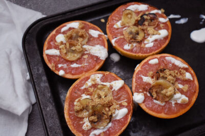 grapefruit halves with toppings on a pan