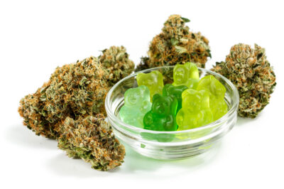 clear bowl filled with gummy bears and marijuana buds around isolated on a white background