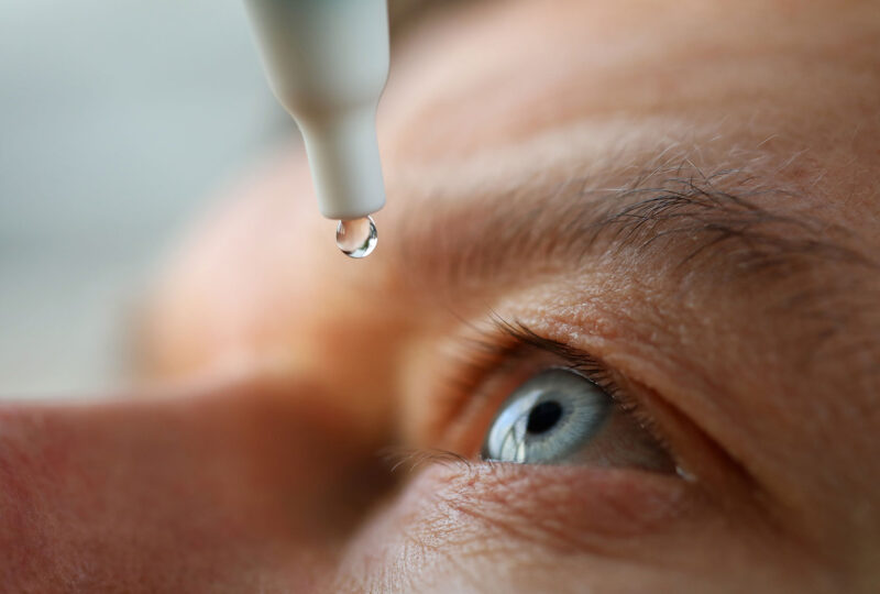 closeup of man putting eye drops on his eye