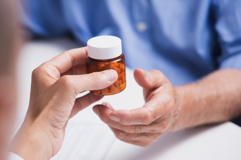 Doctor handing a bottle of pills to a senior man