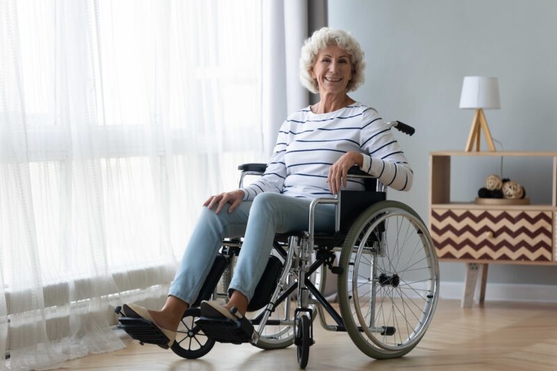 Happy senior woman sitting in wheelchair at home